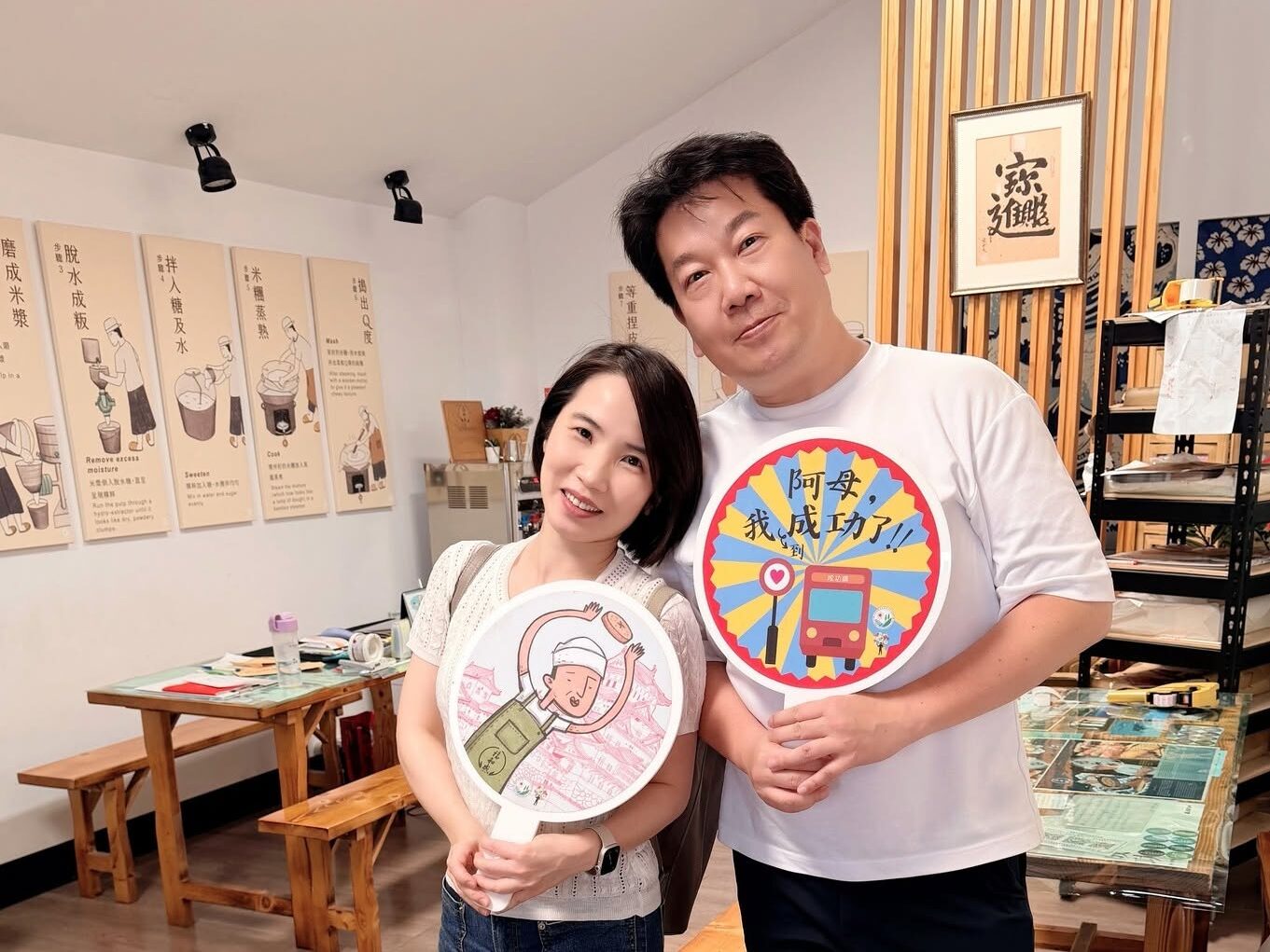 Vito大叔與胡咪老師拿著圓形手拿牌合照，後方是講解粿仔製作步驟的掛畫