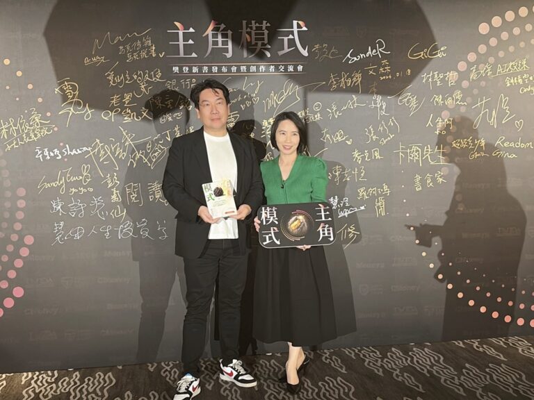 胡咪老師與Vito大叔在《主角模式》新書發布會簽名牆前，手拿《主角模式》書與手牌合照