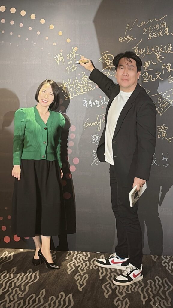 Vito大叔在《主角模式》新書發布會簽名牆上簽名,胡咪老師站在一旁